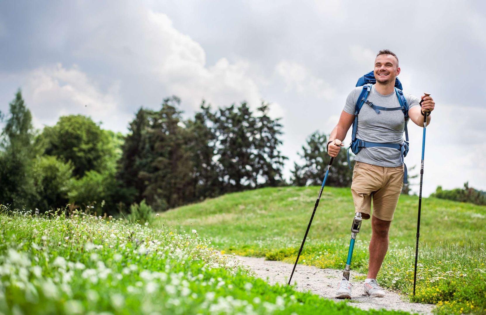 ein Wandernder Mann mit Beinprothese wandert lächelnd im Freien